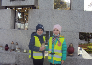 Ala i Karina stawiają znicze pod pomnikiem Harcerzy